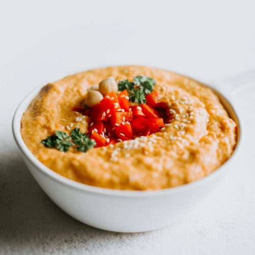 Roasted Red Pepper Hummus with garnishing in a white bowl